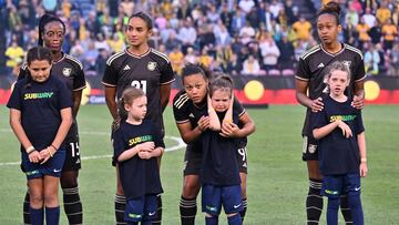 A child blocks her ears to avoid the sound from fire crackers while standing with Jamaica's players for the national anthems during the 2023 Cup of Nations women�s football match between Australia and Jamaica in Newcastle on February 22, 2023. (Photo by SAEED KHAN / AFP) / -- IMAGE RESTRICTED TO EDITORIAL USE - STRICTLY NO COMMERCIAL USE --