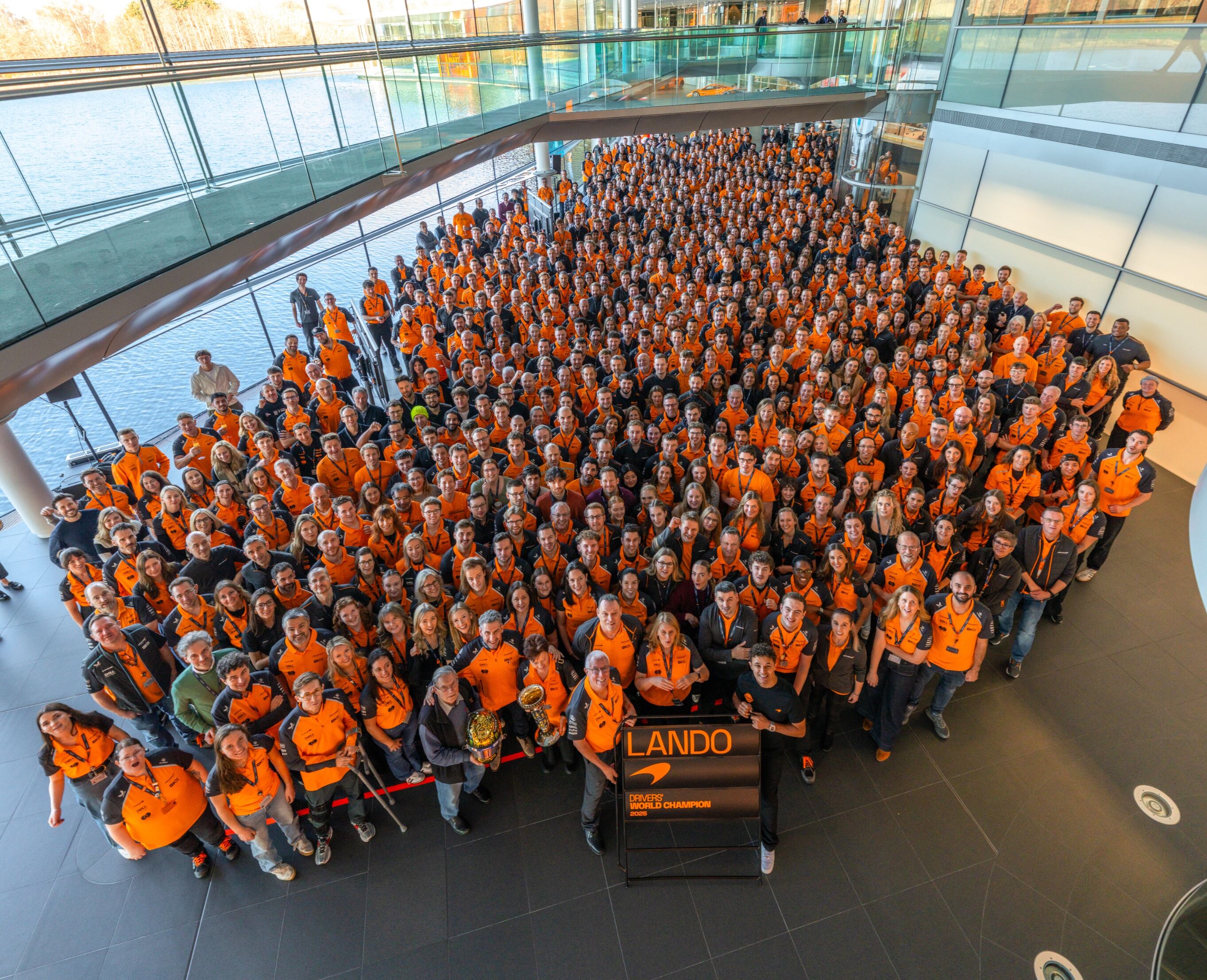 Los trabajadores de McLaren posan junto a Norris y los títulos de F1 en Woking.