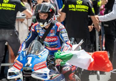 Pecco Bagnaia llega al podio con una bandera de Italia atada s u brazo izquierdo.