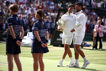 Carlos Alcaraz y Novak Djokovic charlan amistosamente con sus respectivos trofeos de Wimbledon.