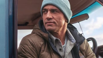 Kelly Slater mira hacia un lado vestido con gorro y chaqueta en el asiento dle concductor de una furgoneta.