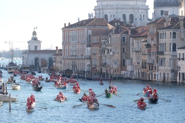 Personas vestidas de Papá Noel reman durantela  regata navideña en el Gran Canal de Venecia.