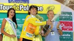 Jon Izagirre, con el maillot amarillo de l&iacute;der, riega feliz a los espectadores desde el podio.