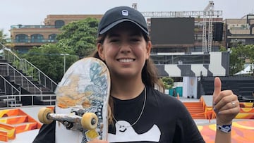 Andrea Benítez con su tabla de skate sonríe y levanta el pulgar.