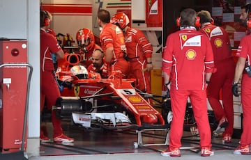 Sebastian Vettel, dentro del coche, espera a que sus mecánicos reparen una avería.