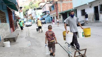 FILE PHOTO: People walk with plastic containers near an unknown water source in the low-income neighbourhood of Petare amid the coronavirus disease (COVID-19) outbreak in Caracas, Venezuela June 3, 2020. REUTERS/Manaure Quintero/File Photo