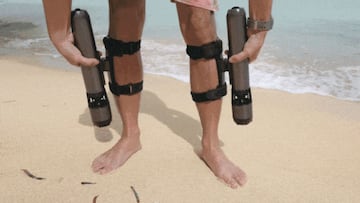 Dos Subnado atados a las piernas de un chico en bañador en la orilla de una playa.