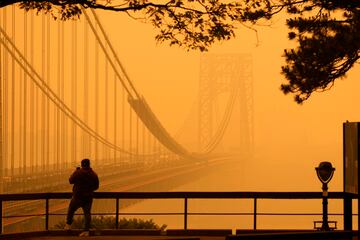 Un hombre habla por teléfono mientras mira a través de la neblina el puente George Washington desde Englewood Cliffs, N.J. 