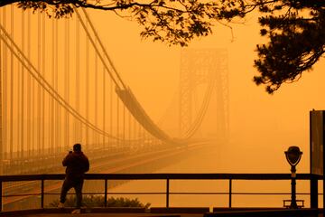 Un hombre habla por tel¨¦fono mientras mira a trav¨¦s de la neblina el puente George Washington desde Englewood Cliffs, N.J.