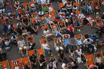 La gente sentada en sillas cómodas mientras ven los partidos de Roland Garros en la pantalla gigante de la pista principal.