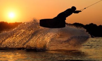 Preciosa imagen de una persona practicando kitesurf al atardecer en un lago de la ciudad de Garbsen en la región de Hanover.