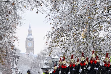 Miembros de la Household Cavalry pasea bajo los árboles cubiertos de nieve frente a la Torre Elizabeth, más comúnmente conocida como Big Ben, mientras continúa el clima frío, en Londres.