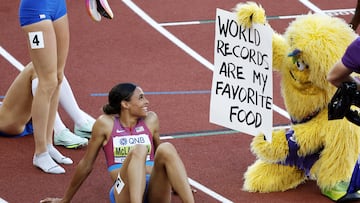 Sydney McLaughlin mira sonriente a la mascota 'Bigfoot' por su ocurrencia.