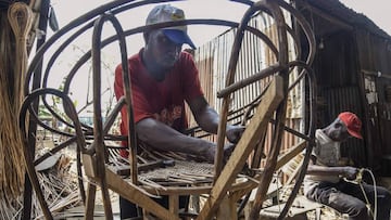 In this photograph taken on August 27, 2020, a man weaves cane onto a wooden chair frame at Nigeria's largest cane 'village' under the bridge at Mende in the Maryland District of Lagos. - Cane craft in Nigeria, Africa's most populous c
