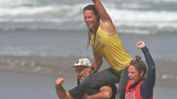 Tres surfistas salen del agua con el pu&ntilde;o levantado durante el XX Salinas Longboard Festival Castrill&oacute;n (Asturias).