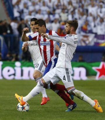 El centrocampista del Atlético de Madrid Koke Resurrección con el balón ante los jugadores del Real Madrid Sergio Ramos  y el colombiano James Rodríguez, durante el partido de ida de cuartos de final de Champions League.