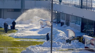 Operarios intentando limpiar el césped de la Ciudad Deportiva.