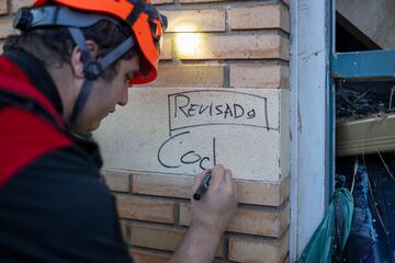 Una persona del servicio de emergencias apunta que un edificio está revisado en Alfafar, Valencia.