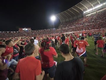 Jugadores y aficionados del Mallorca celebran sobre el terreno de juego el regreso de su equipo a la máxima categoría del fútbol español.