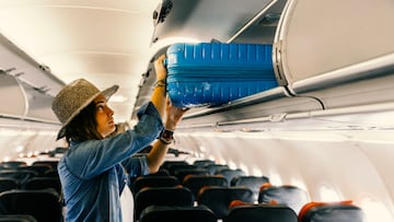 Woman passenger storing luggage above her seat in an airplane