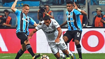 Arthur (L) and Cortez (R) of Brazilx92s Gremio, vie for the ball with Jose Sand of Argentina's Lanus, during their Copa Libertadores 2017 first leg final match at Arena Gremio stadium, in Porto Alegre, Brazil on November 22, 2017. / AFP PHOTO / NELSO