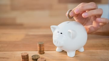 Close-up of hand inserting coin in piggy bank