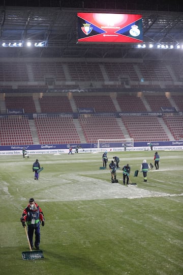 Operarios del club rojillo quitan la nieve del terreno de juego.