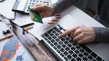 Cropped view of business person working on laptop computer, holding credit card and doing online banking