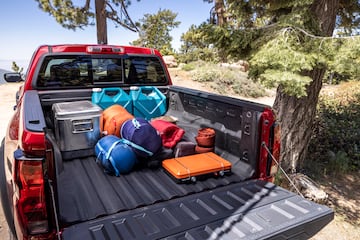 Rear view of truck with tailgate down and camping equipment in truck bed.