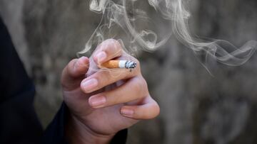Closeup hand holding lighted cigarrette in private area. TABACO CAJETILLA DE TABACO