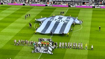 Los jugadores de Newcastle y Tottenham saltan al césped de St. James' Park mientras se despliega una gran camiseta con las siglas del Royal National Institute for Deaf People (RNID).