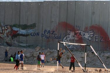 Jóvenes palestinos juegan al fútbol junto a un tramo de la barrera de separación israelí, en la aldea cisjordana de Abu Dis, a las afueras de Jerusalén.
