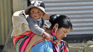 An indigenous woman carrying a baby walks at a low-income area in El Alto, on May 22, 2020, amid the new coronavirus pandemic. (Photo by AIZAR RALDES / AFP)