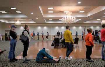 Una mujer se sienta y se estira mientras espera para votar mientras el Centro de Herencia Italiana ha tenido una fila de más de una hora desde las 7 a.m. durante las elecciones presidenciales estadounidenses de 2024 el día de las elecciones en Portland, Maine, EE. UU.