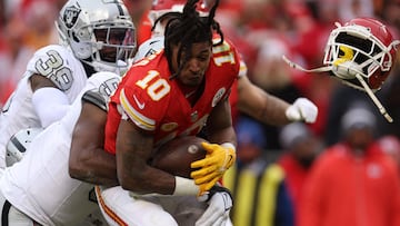 KANSAS CITY, MISSOURI - DECEMBER 25: Isiah Pacheco #10 of the Kansas City Chiefs loses his helmet as he's tackled by Divine Deablo #5 of the Las Vegas Raiders during the third quarter at GEHA Field at Arrowhead Stadium on December 25, 2023 in Kansas City, Missouri. Jamie Squire/Getty Images/AFP (Photo by JAMIE SQUIRE / GETTY IMAGES NORTH AMERICA / Getty Images via AFP)