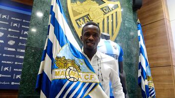 Kon&eacute;, posando con una bandera del M&aacute;laga y el escudo de fondo.