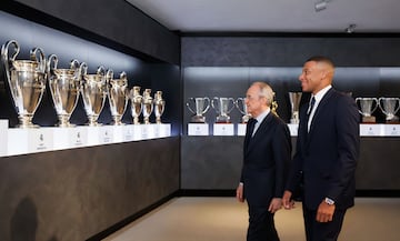 Kylian Mbappé y Florentino Pérez viendo la sala de trofeos del Real Madrid. 