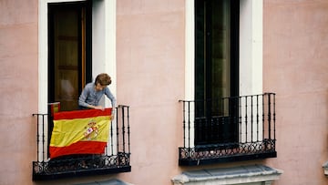 MADRID, SPAIN - JUNE 19: (EXCLUSIVE COVERAGE - PREMIUM PRICING APPLIES) A woman hangs a Spanish flag from her balcony at Plaza de Oriente opposite of the Royal Palace prior to the King's official coronation ceremony on June 19, 2014 in Madrid, Spain. The coronation of King Felipe VI is held in Madrid. His father, the former King Juan Carlos of Spain abdicated on June 2nd after a 39 year reign. The new King is joined by his wife Queen Letizia of Spain. (Photo by Pablo Blazquez/CP/Getty Images)