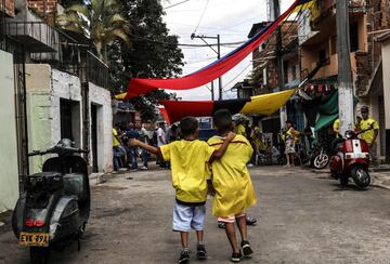 Dos niños llevan la camiseta de la selección colombiana mientras gritan y cantan la victoria contra Senegal.
