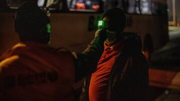 A mine employee measures the temperature of a mine worker, en route to his evening shift at the Sibanye-Stillwater platinum mine, before letting him board a company bus at the Wonderkop taxi rank in Marikana, near Rustenburg, on May 15, 2020. - The mines 