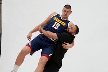 Sólo quedan tres semanas para el inicio de la temporada en la NBA (24 de octubre) y los equipos se ponen en marcha, con entrenamientos y sesiones de fotos. En la de los Denver Nuggets, actuales campeones, se dio esta imagen divertida. Claus Antunes de Souza, preparador físico del equipo, levantando a pulso los 128 kilos de Nikola Jokic.