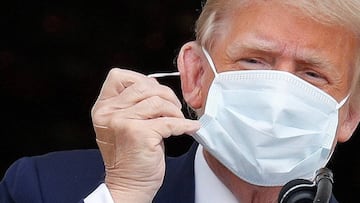 U.S. President Donald Trump takes off his face mask as he comes out on a White House balcony to speak to supporters gathered on the South Lawn for a campaign rally that the White House is calling a &quot;peaceful protest&quot; in Washington, U.S., October