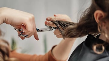 Human hands hair cut using a scissors lock of hair