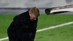 Barcelona&#039;s Dutch coach Ronald Koeman protects himself from the rain during the &quot;El Clasico&quot; Spanish League football match between Real Madrid CF and FC Barcelona at the Alfredo di Stefano stadium in Valdebebas, on the outskirts of Madrid o