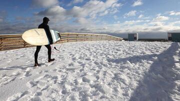 LONG BEACH, NEW YORK - DECEMBER 17: A man walks on the boardwalk to go surfing on December 17, 2020 in Long Beach, New York. Many parts of the Northeast were hit with heavy snowfall in the first big storm of the season.   Al Bello/Getty Images/AFP
 == FOR