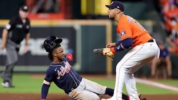 HOUSTON, TEXAS - OCTOBER 27: Ozzie Albies #1 of the Atlanta Braves slides in safely back to first base after a fly out as Yuli Gurriel #10 of the Houston Astros looks on during the eighth inning in Game Two of the World Series at Minute Maid Park on Octob