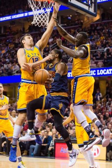 Andrew Bogut y Draymond Green de los Warriors intentan bloquear a Kyrie Irving.