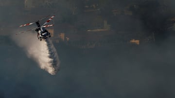 An helicopter makes a drop as smoke billows from the Palisades Fire threatening homes in the Brentwood area of Los Angeles, California, U.S., January 11, 2025. REUTERS/Shannon Stapleton