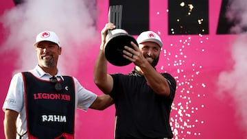 Spain's Jon Rahm (R) lifts the trophy with his caddie Adam Hayes after winning the LIV Golf Invitational Series event at the JCB Golf and Country Club in Rocester, central England, on July 28, 2024. (Photo by HENRY NICHOLLS / AFP)