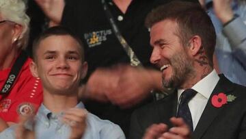 David Beckham y su hijo Romeo aplaudiendo en un evento.